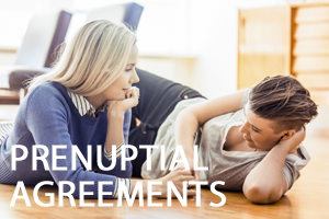 Two women laying on the floor with prenuptial agreements written in white text in front of them.